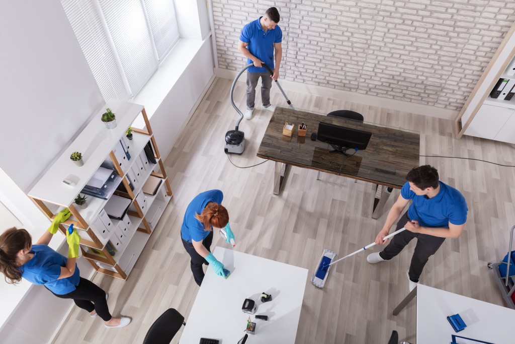 Group Of Janitors In Uniform Cleaning The Home With Cleaning Equipment